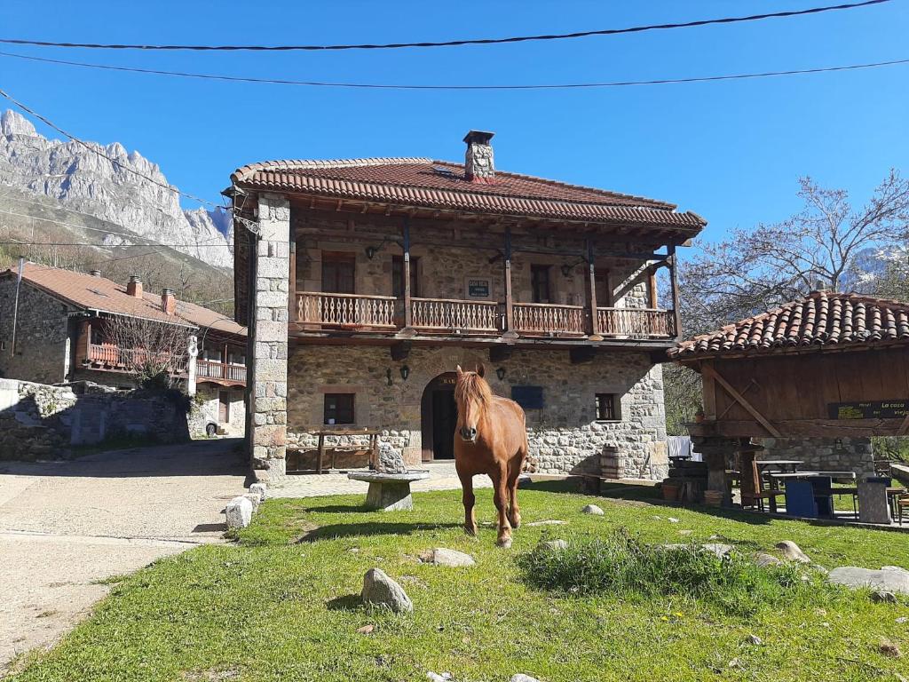 un caballo parado en el césped frente a un edificio en La Casa Vieja en Valdeón, en Soto de Valdeón