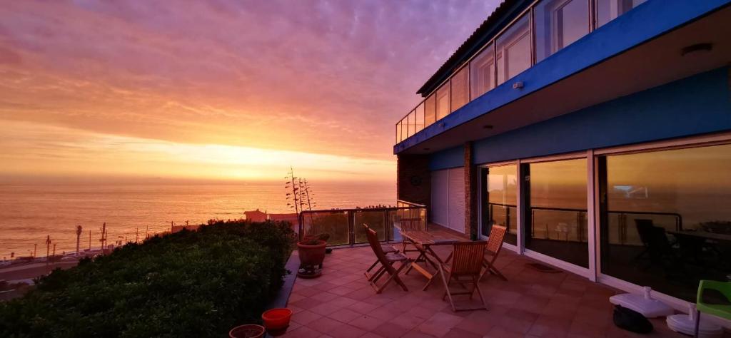 a house with a view of the ocean at sunset at Mega Ocean Magoito - Sintra in Sintra