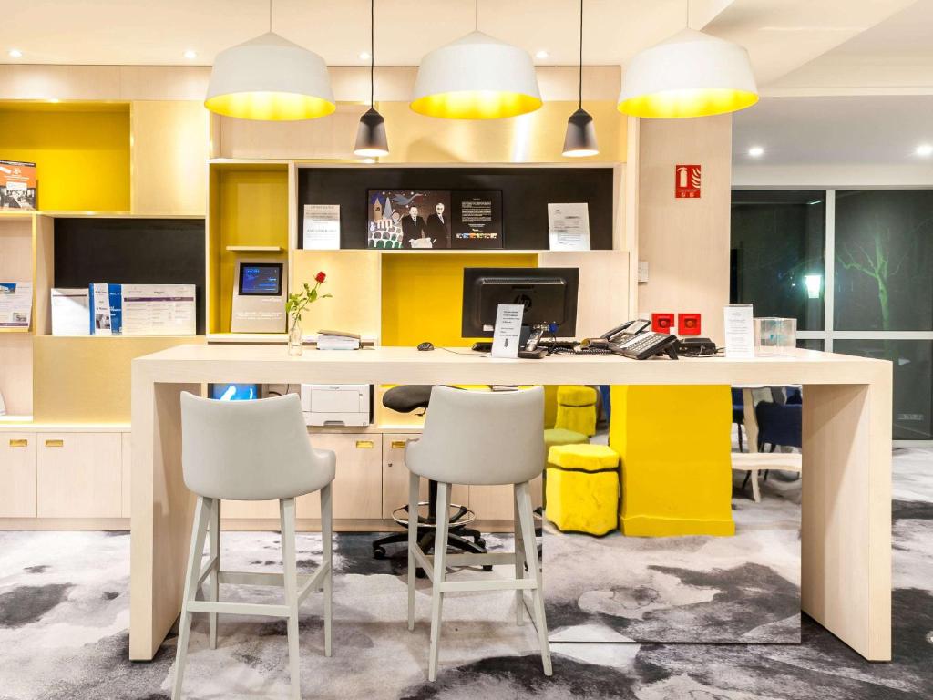 een kantoor met een geel en wit bureau en stoelen bij Hôtel Mercure Mâcon Bord de Saône in Mâcon