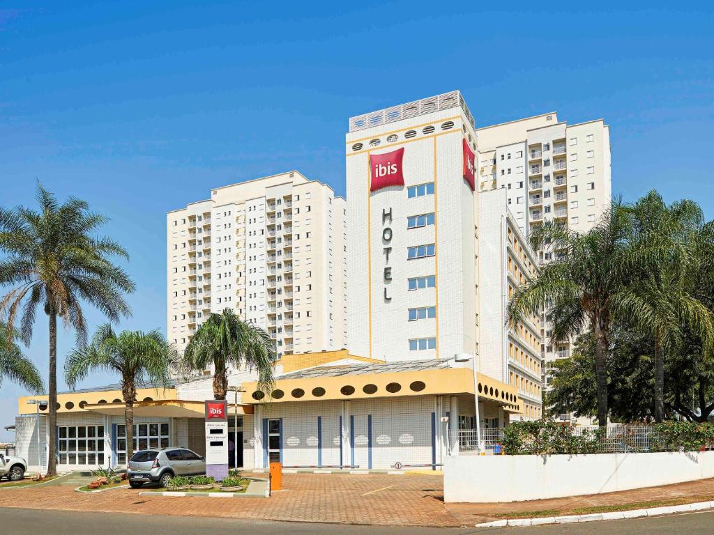 a large building with palm trees in front of it at Ibis São Carlos in São Carlos