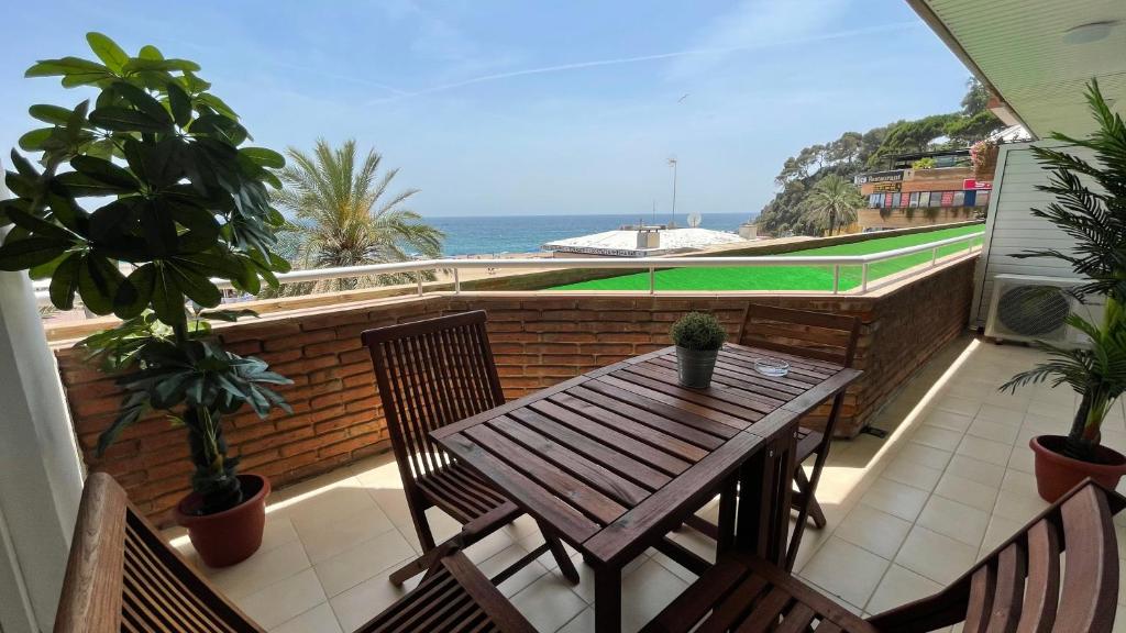 una mesa de madera y sillas en un balcón con una pista de tenis en Apartments Paradise Lloret, en Lloret de Mar