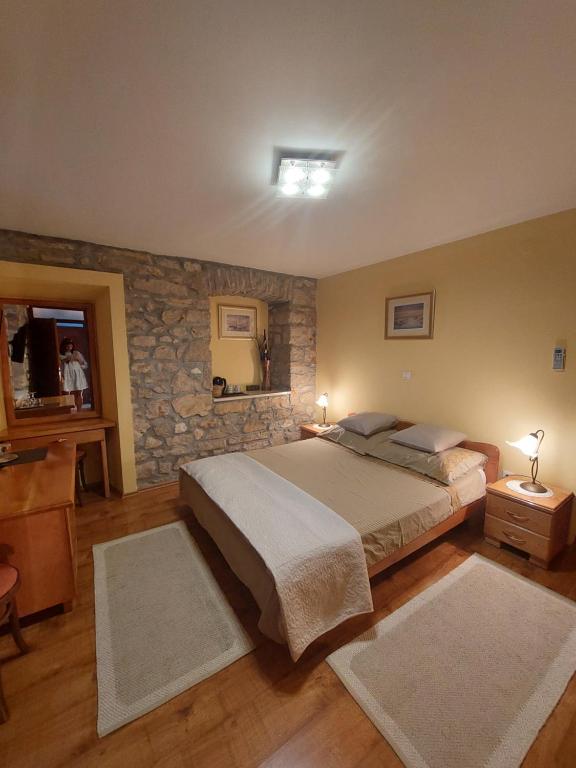 - une chambre avec un grand lit et un mur en pierre dans l'établissement Guest house Paola, à Primošten