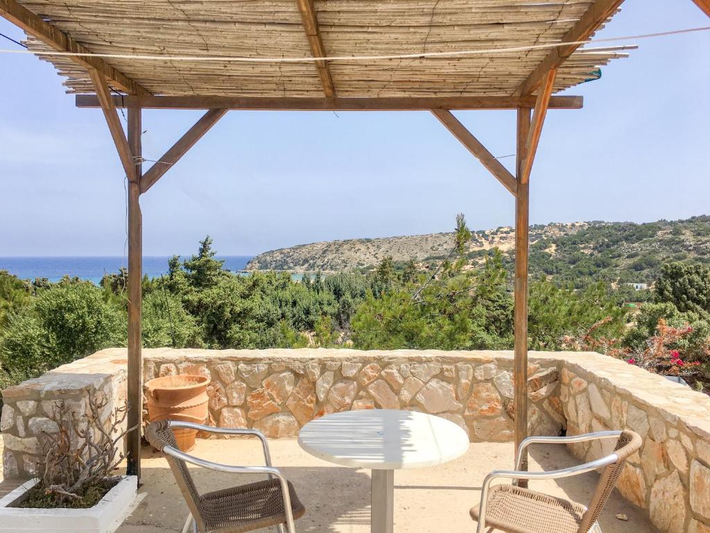eine Terrasse mit einem Tisch, Stühlen und einer Steinmauer in der Unterkunft Consolas Gavdos Studios in Gavdos