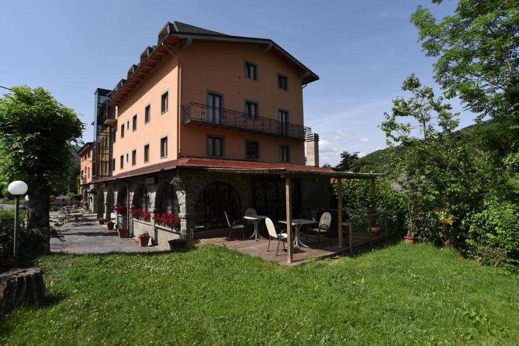 a large building with tables and chairs in a yard at Albergo Bucaneve in Pievepelago