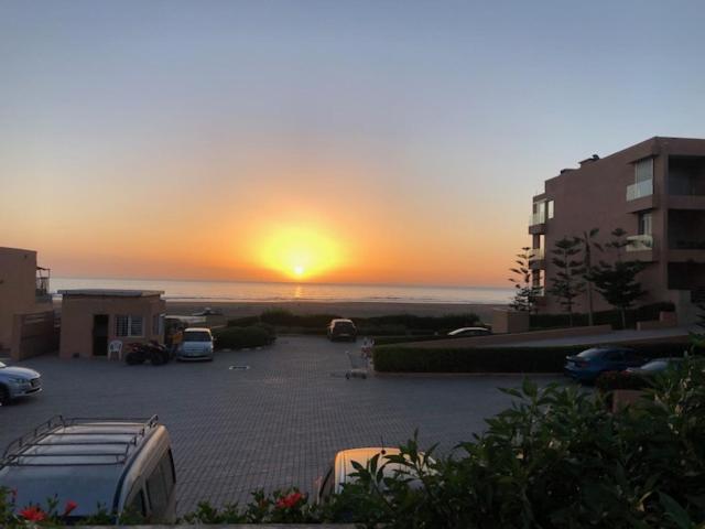 un coucher de soleil sur un parking avec des voitures garées dans l'établissement Luxueux appartement pied dans l'eau sur la plage d'Imi Ouaddar, à Agadir nʼ Aït Sa