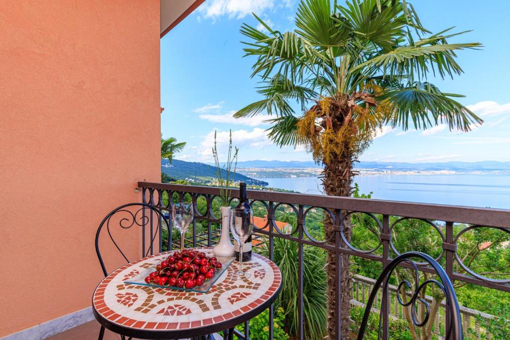 a table with fruit on a balcony with a palm tree at Apartments Jasminka Lovran in Lovran