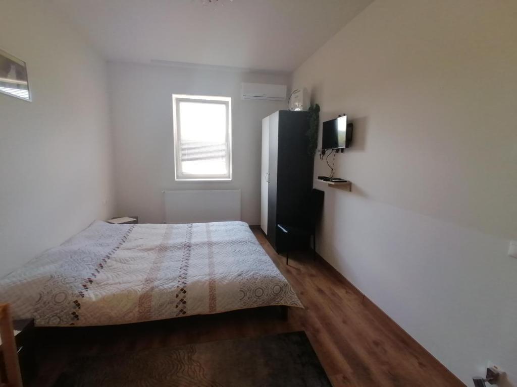 a white bedroom with a bed and a window at ZOLDAV in Nyíradony