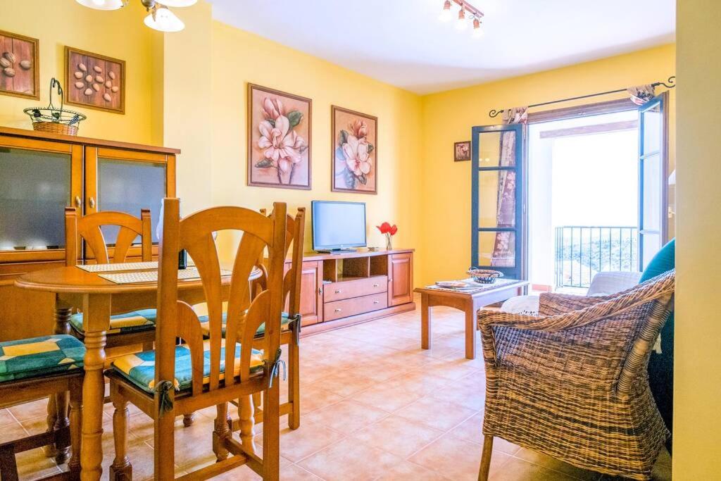 ein Wohnzimmer mit einem Tisch, Stühlen und einem TV in der Unterkunft Bonito apartamento Piscina Wifi in Frigiliana