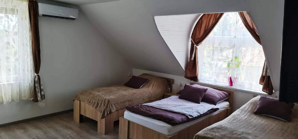 a room with two beds and a window at Arató Vendégház in Pécs