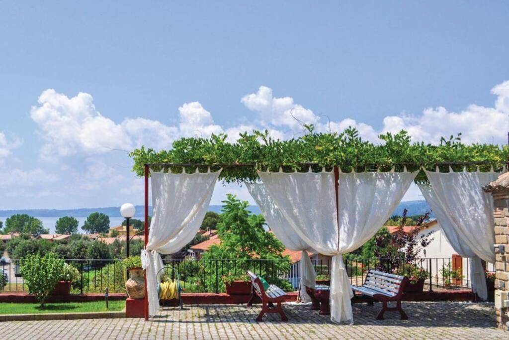 un pabellón con cortinas blancas y bancos en un patio en La Cupoletta -Holiday House - GILDA en Trevignano Romano