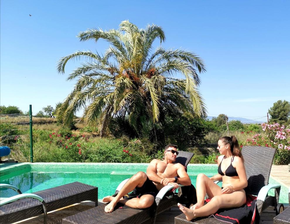 mężczyzna i kobieta siedzący na krześle obok basenu w obiekcie Casona Granado w mieście El Pilar y Provincias
