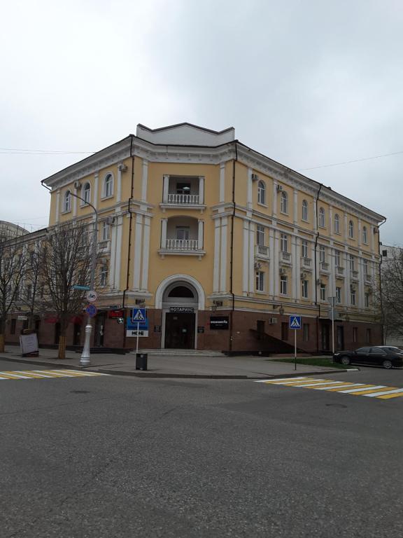 a large yellow building on the corner of a street at Отель НОХЧОСТАР in Groznyy