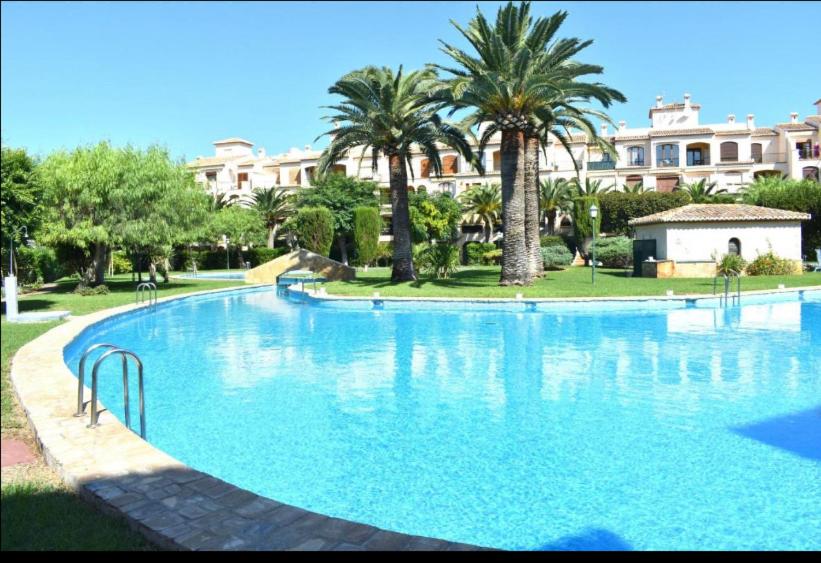 a large swimming pool with palm trees and a building at BUNGALOW LA ISLA in Jávea
