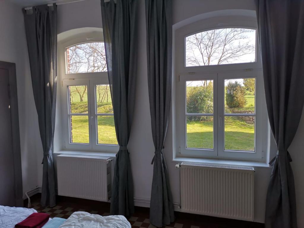 two windows in a bedroom with curtains at Gutshaus Thorstorf FeWo Wismar in Thorstorf