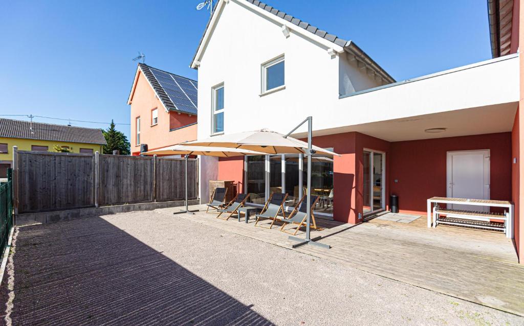 a patio with chairs and an umbrella on a house at LES MAISONS SOLAIRES Contact O6614O9II9 Villa pour 15 pers maxi in Griesheim-près-Molsheim