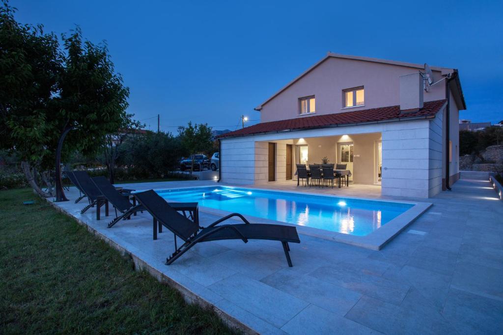 a swimming pool with chairs next to a house at Villa Fig in Split