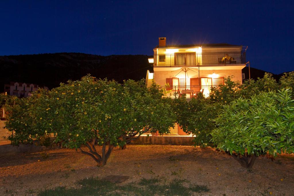 a house with an orange tree in front of it at Apartments Popaj in Komiža