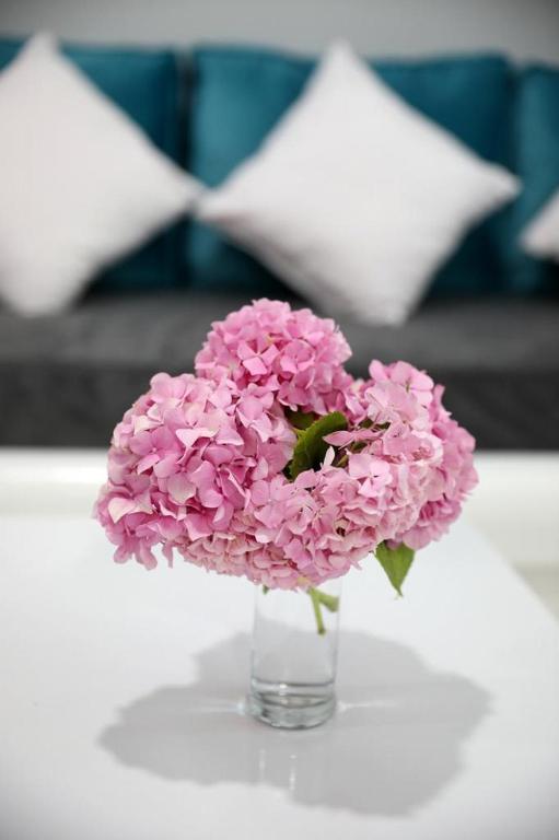 a glass vase filled with pink flowers on a table at Guest House Narta in Vlorë