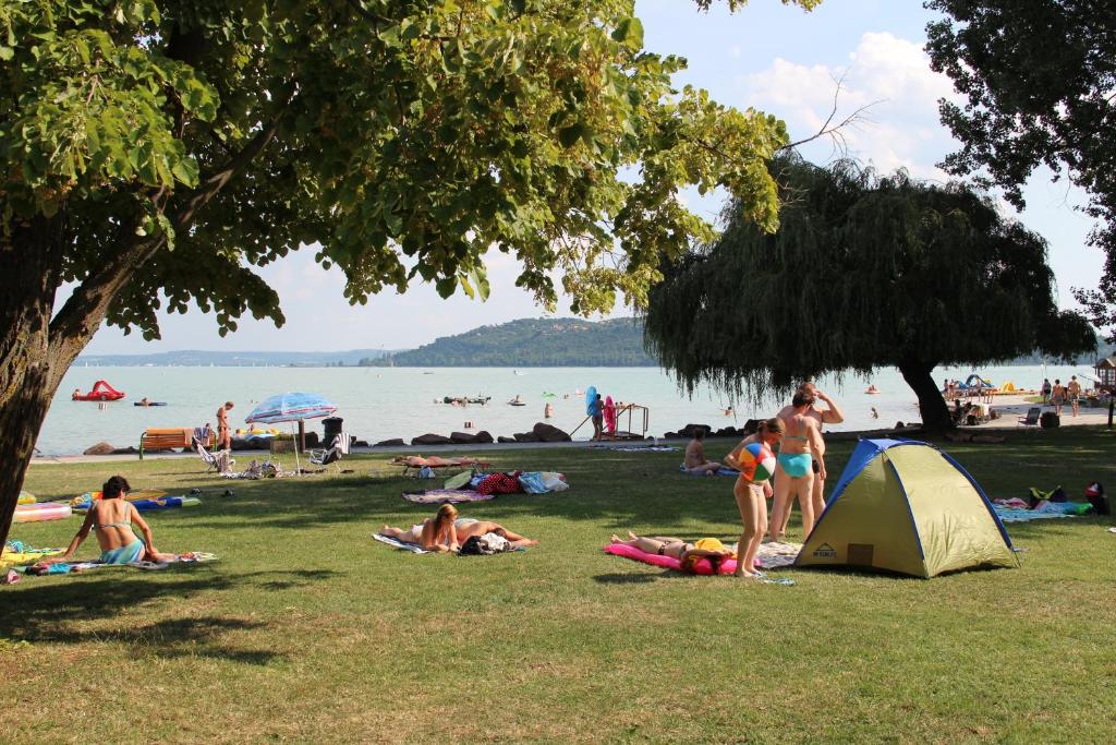 grupa ludzi leżących na trawie na plaży w obiekcie Happy Camp mobile homes in BalatonTourist Füred Camping & Bungalows w Balatonfüred