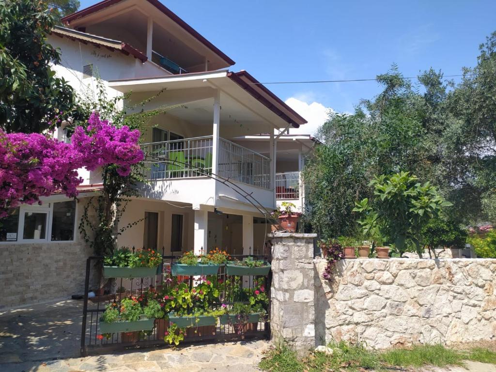 ein weißes Haus mit Blumen auf einem Zaun in der Unterkunft Bucak Apart Hotel Göcek & Beach in Göcek