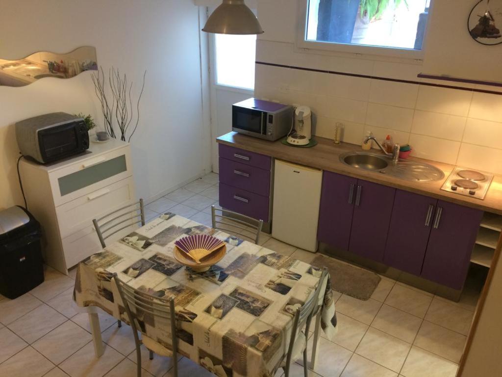 uma cozinha com uma mesa com cadeiras e um micro-ondas em Logement aux portes de Montpellier em Lavérune