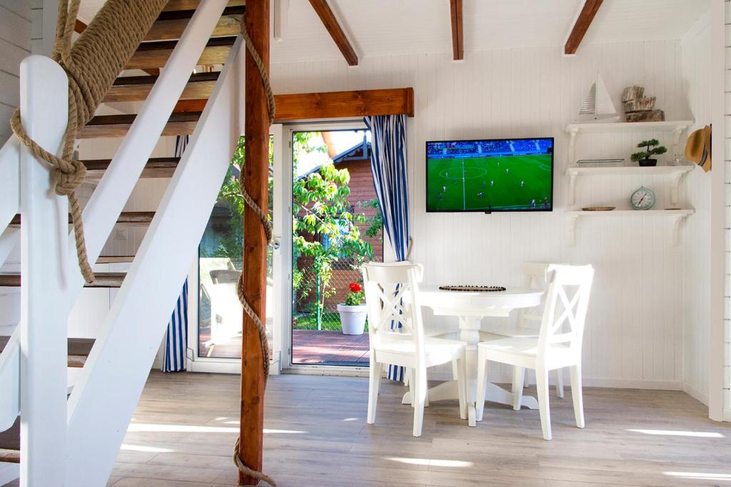 a dining room with a table and chairs and a tv at Domek całoroczny nad morzem Stegna Baltica in Stegna