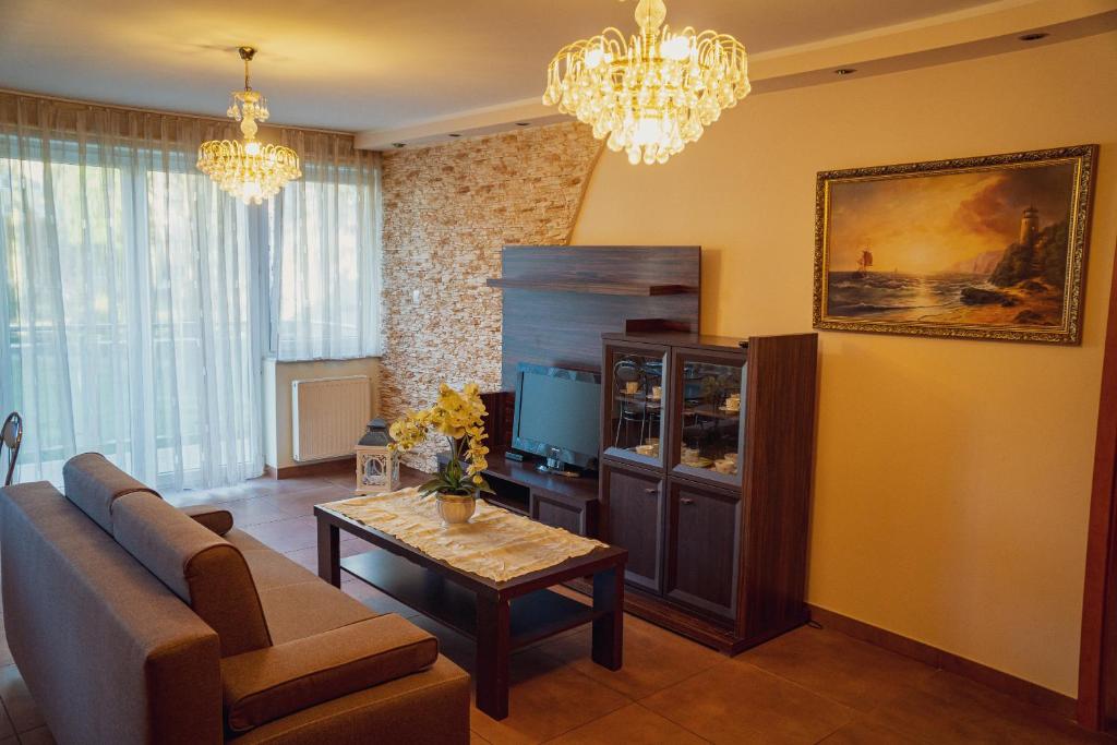 a living room with a couch and a tv and a table at Apartament Morski Piasek in Władysławowo