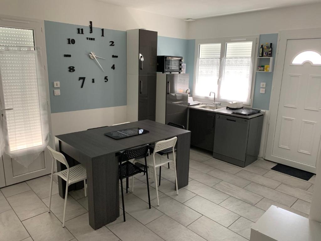 a kitchen with a table and a clock on the wall at Idéale famille, tout y est ! in Dompierre-sur-Besbre