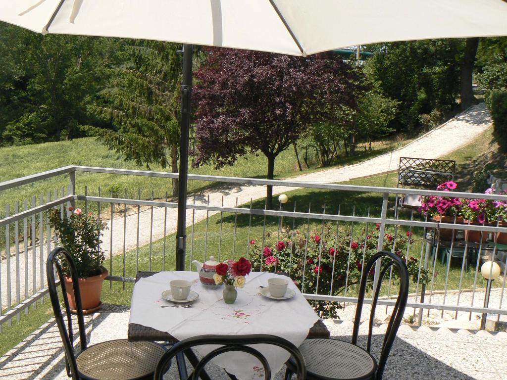 een tafel en stoelen op een balkon met een parasol bij B&B Le Cerque in Crocicchia