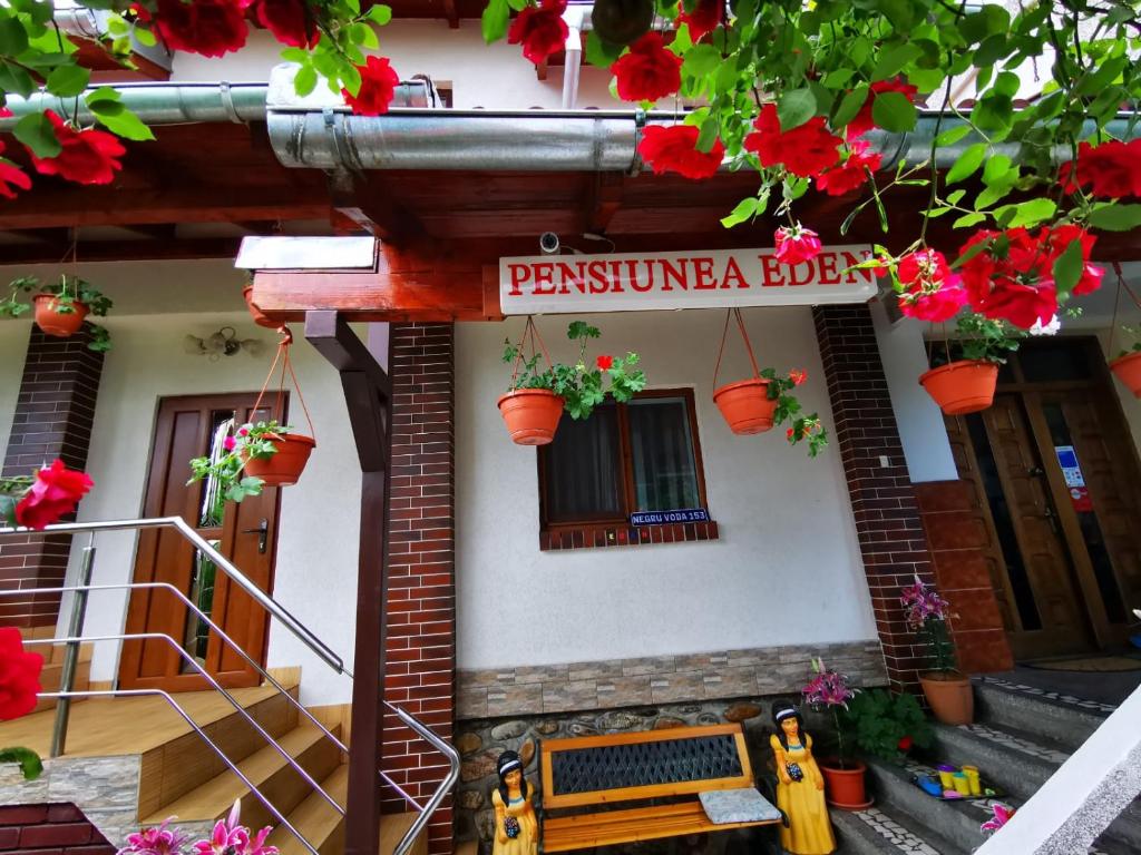 una señal en el lado de un edificio con flores en Pensiunea Eden, en Curtea de Argeş