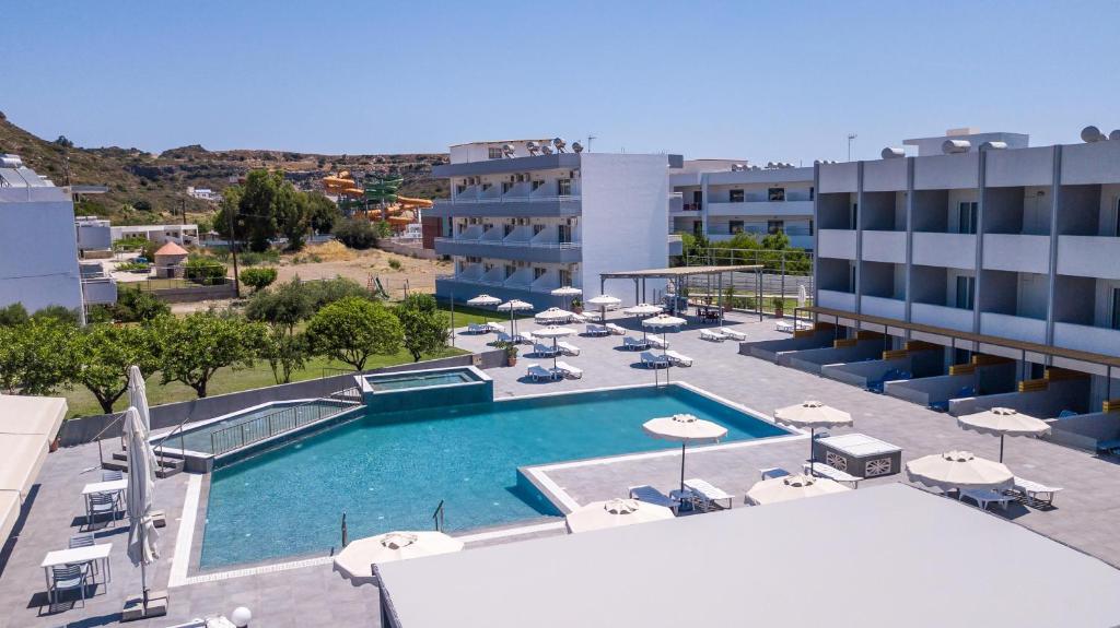 una piscina con sombrillas y sillas y un edificio en Tsampika Hotel Faliraki en Faliraki