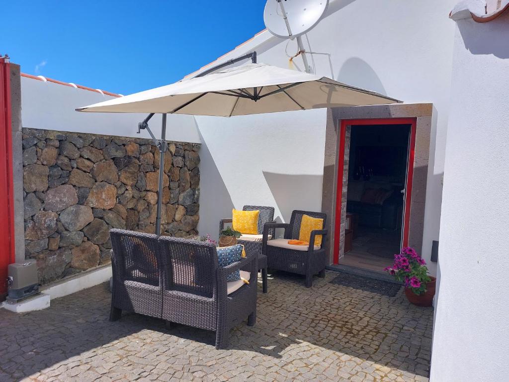 a patio with two chairs and an umbrella at Casa das Cales in Angra do Heroísmo