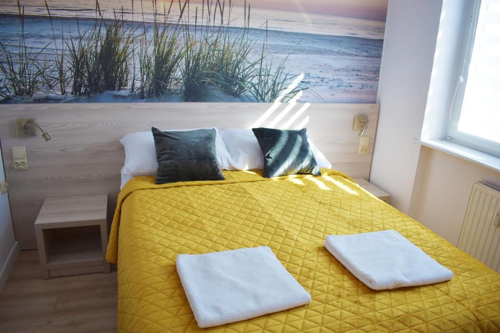 1 dormitorio con 1 cama amarilla y 2 toallas en Apartament Assolato, en Władysławowo