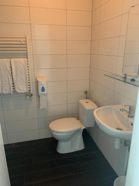a white toilet sitting next to a sink in a bathroom at Stadshotel Vlissingen in Vlissingen