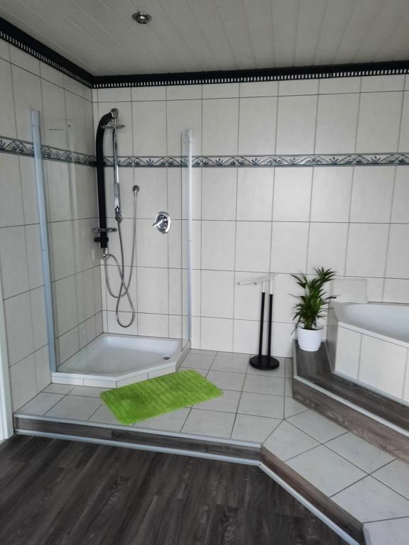 baño con ducha y alfombra verde en Haus Heidi, en Rüber
