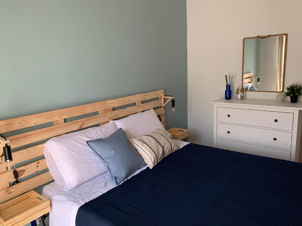 a bedroom with a bed with a wooden headboard and a mirror at Da Nonno Antonio in Santa Teresa di Riva
