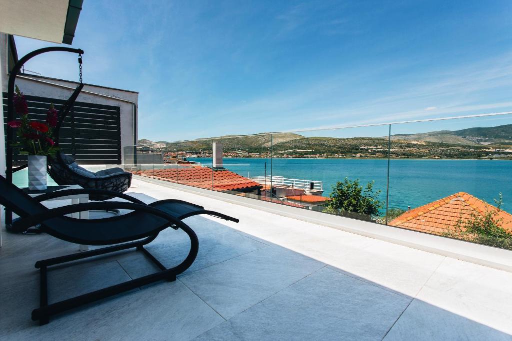 a bench on a balcony with a view of the water at Villa Magna - seaside villa with pool and sauna in Trogir