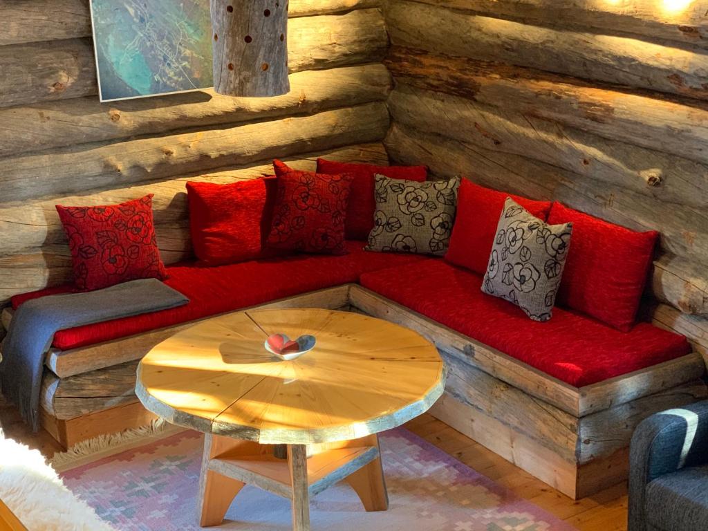 a living room with a red couch and a table at Logwood Chalet in Luosto