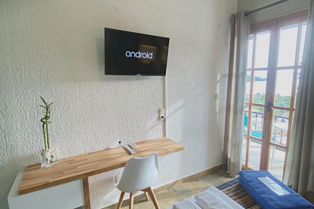 a room with a desk and a tv on the wall at Panormos Beach Hotel Skopelos in Panormos Skopelos