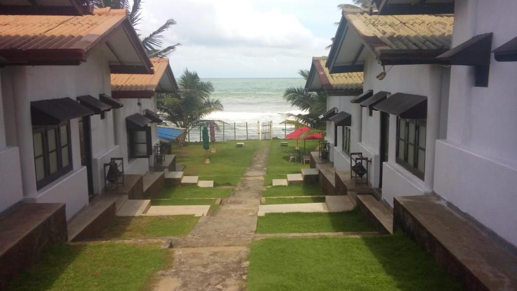 uma vista para a praia entre duas casas em Ramon beach resort em Ambalangoda