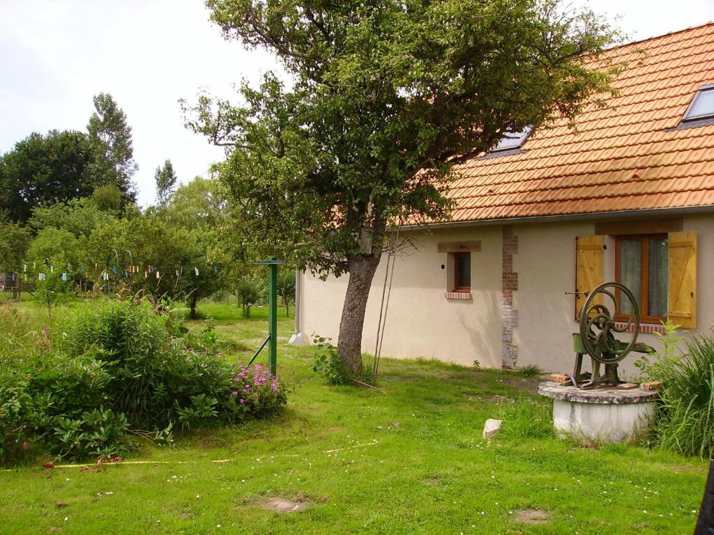 a house with a tree and a bench in the yard at Au Grand Pré in Theillay