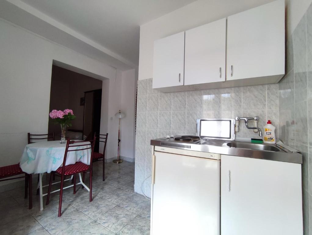 une cuisine avec des placards blancs et une table avec une table dans l'établissement Apartmani Djedovic 2, à Petrovac na Moru
