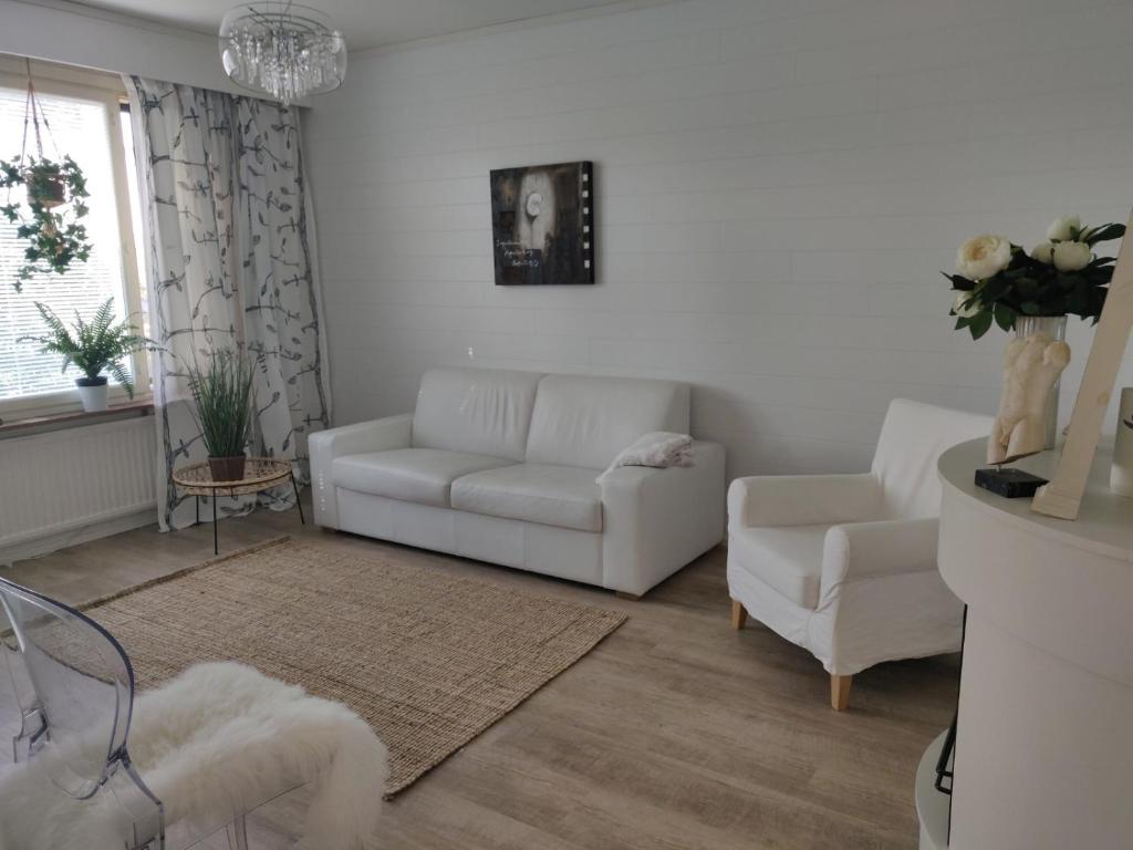 uma sala de estar com um sofá branco e cadeiras em Yyterin valkoinen huoneisto 14A talo B 21 em Pori