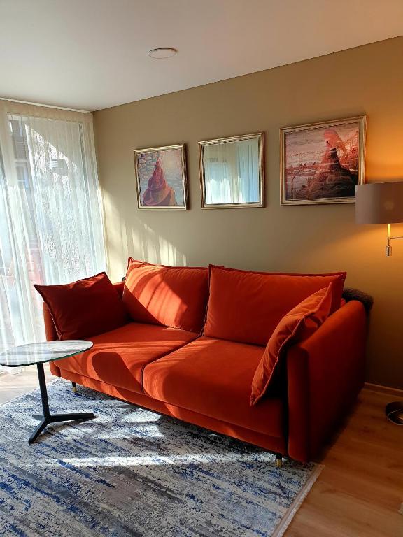 a red couch in a living room with a table at Orange Studio in Juodkrantė