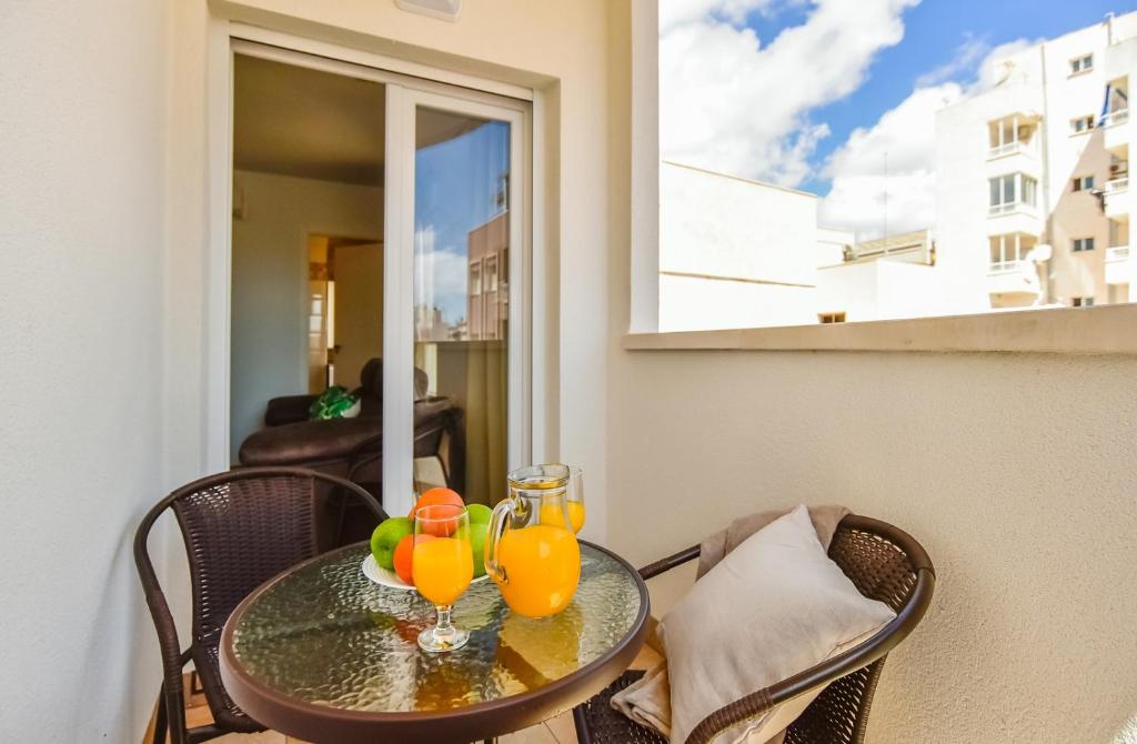 a glass table with two orange juice glasses on it at Apartments CURA BEACH in Torrevieja
