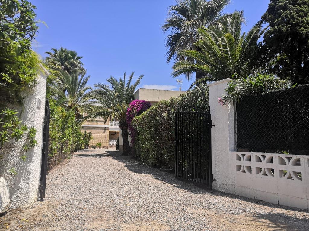 ein Tor zu einem Haus mit Palmen und einer Einfahrt in der Unterkunft Bungalows Peikert - 40a in Sagunt