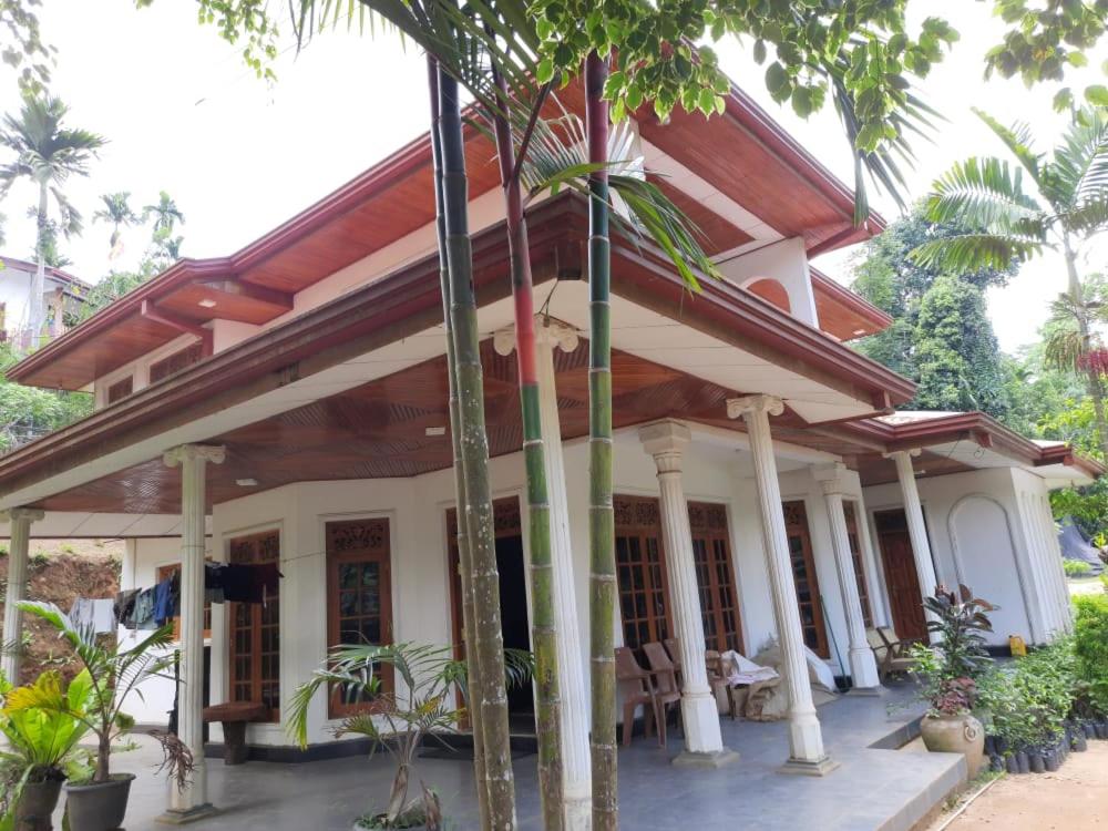 a house with a porch with palm trees at Family Holiday Inn in Badulla