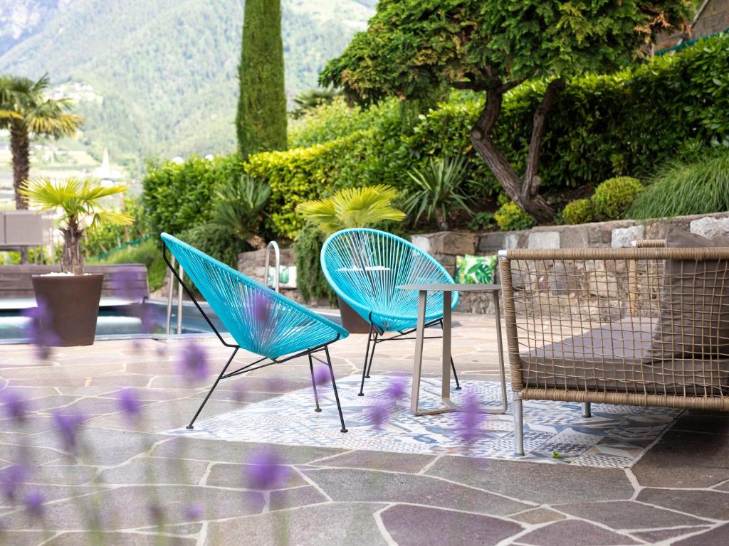 3 chaises bleues assises sur une terrasse avec des fleurs violettes dans l'établissement Hotel Weingut Innerleiterhof, à Schenna