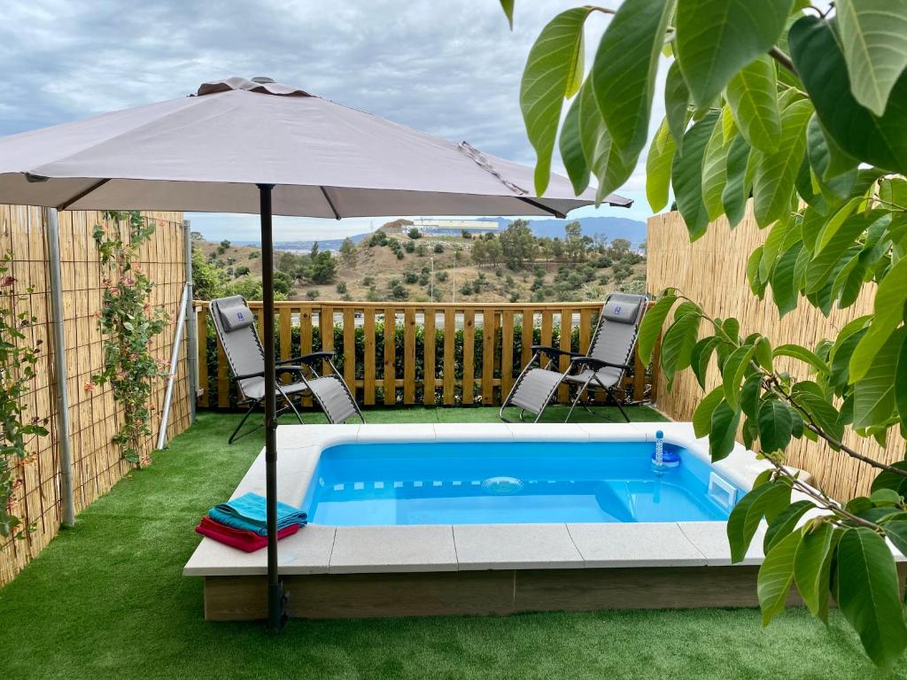 a swimming pool with an umbrella and two chairs and a table at Suite Apto de Invitados- Heated Pool-Piscina Climatizada- Montes de Málaga in Málaga