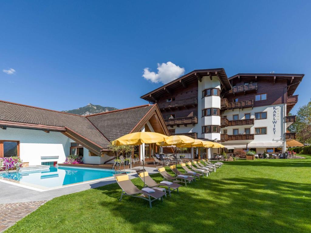 um hotel com cadeiras e guarda-sóis ao lado de uma piscina em Hotel Karlwirt em Pertisau